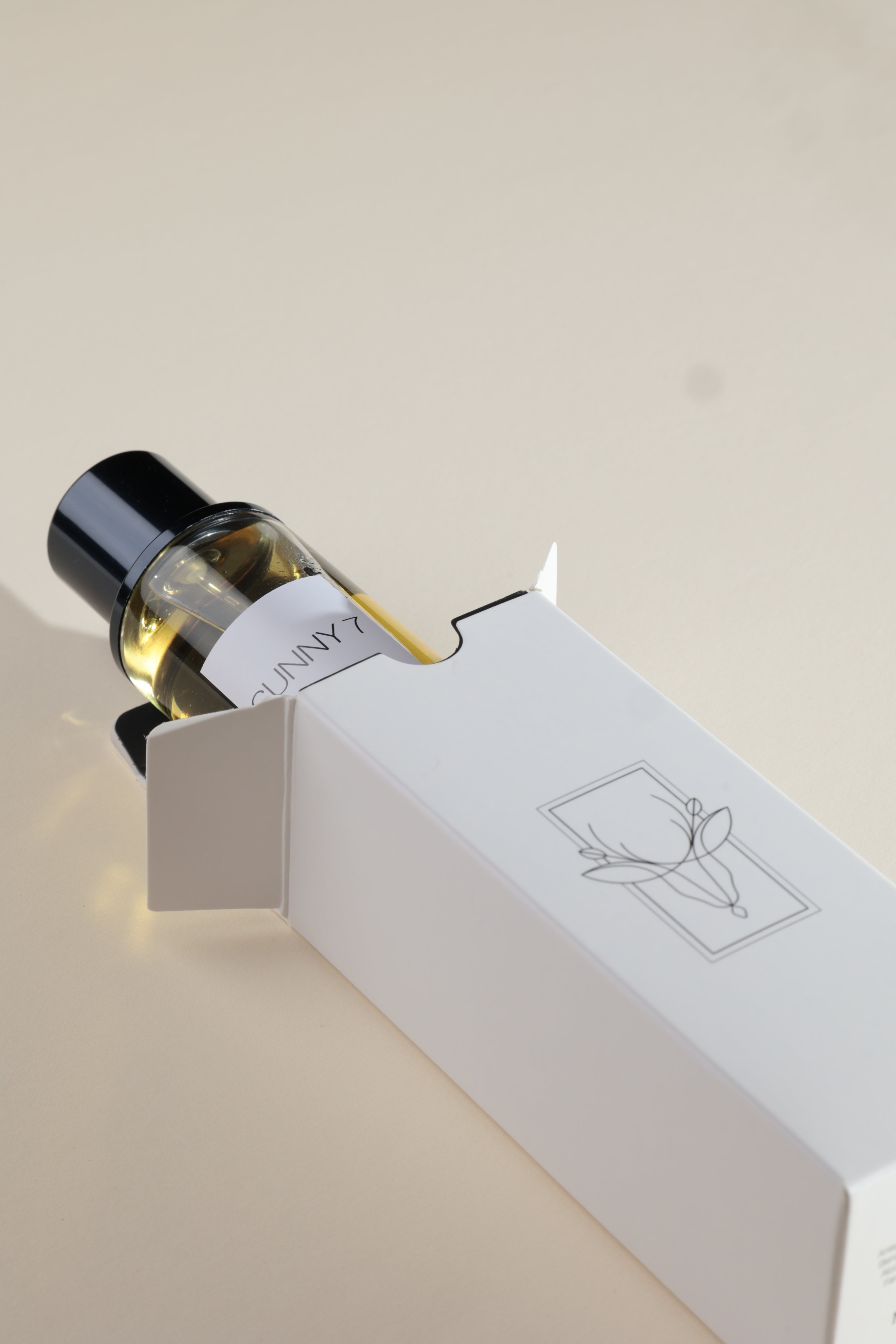 Bottle of perfume with a white box featuring a logo on a light background